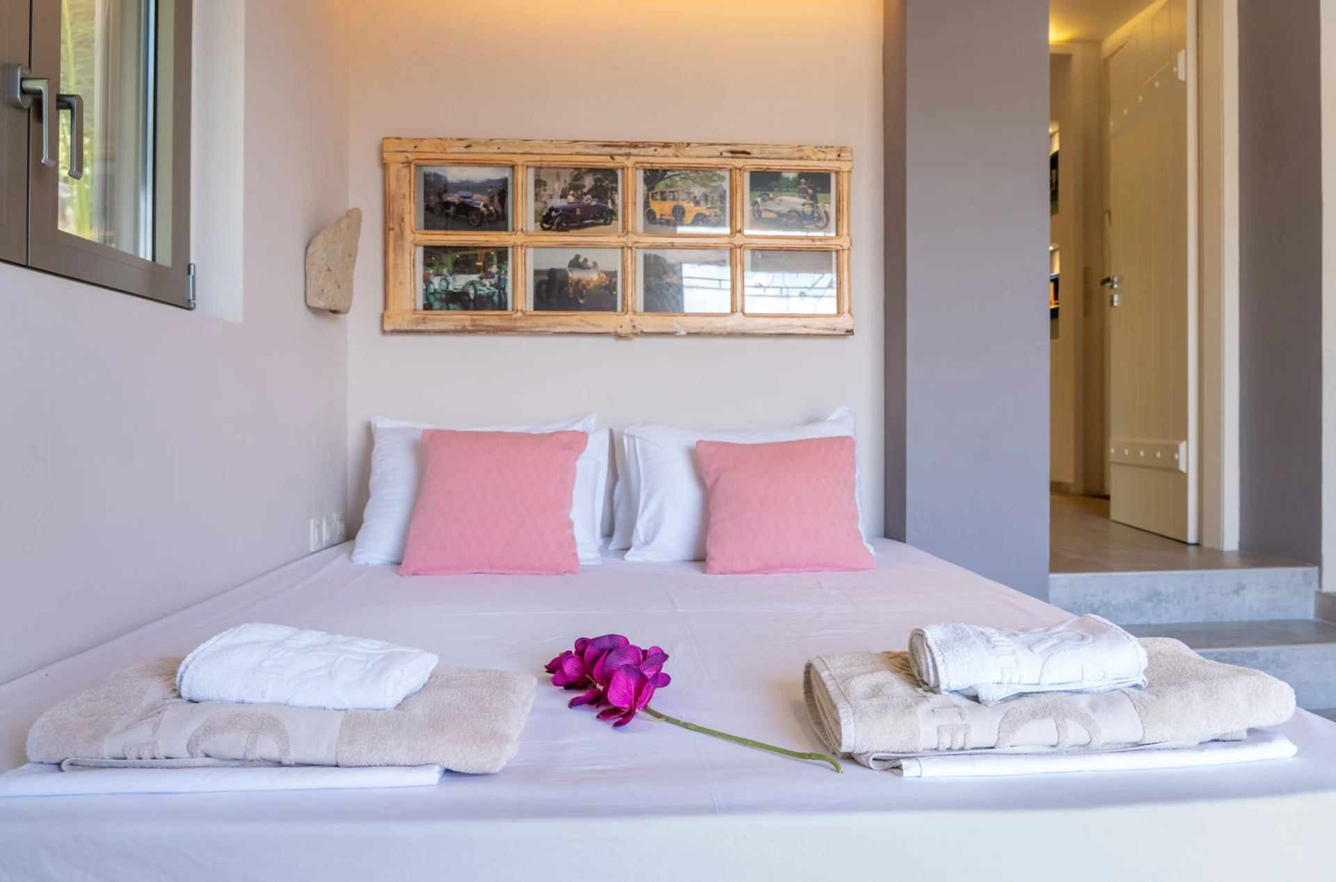Un letto con cuscini rosa cipria sotto il pannello incorniciato nella Alessia Family Suite di CORE Luxury Suites, Skiathos.