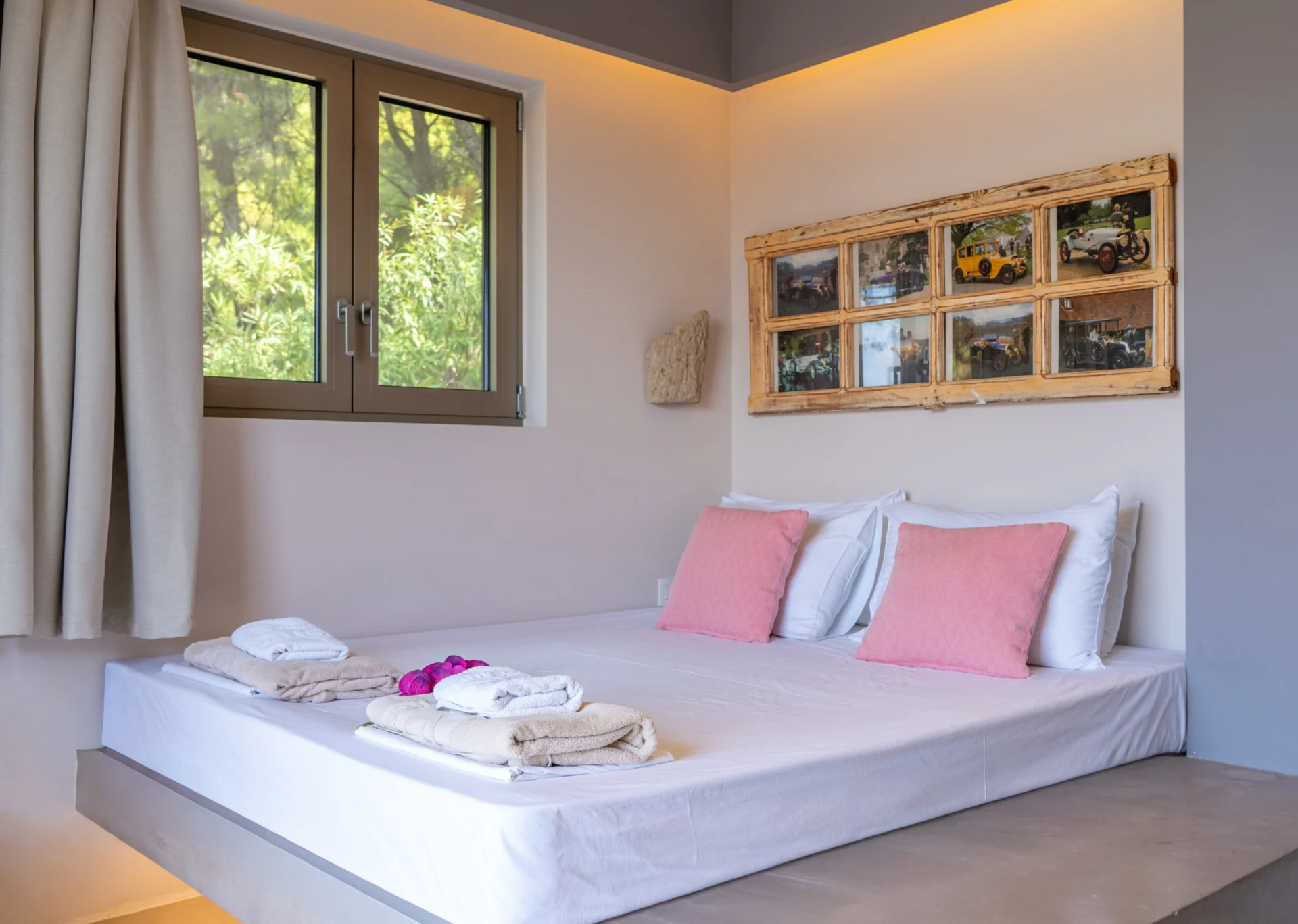Un letto con cuscini rosa cipria sotto un pannello di fotografie incorniciate nella Alessia Family Suite di CORE Luxury Suites, Skiathos.