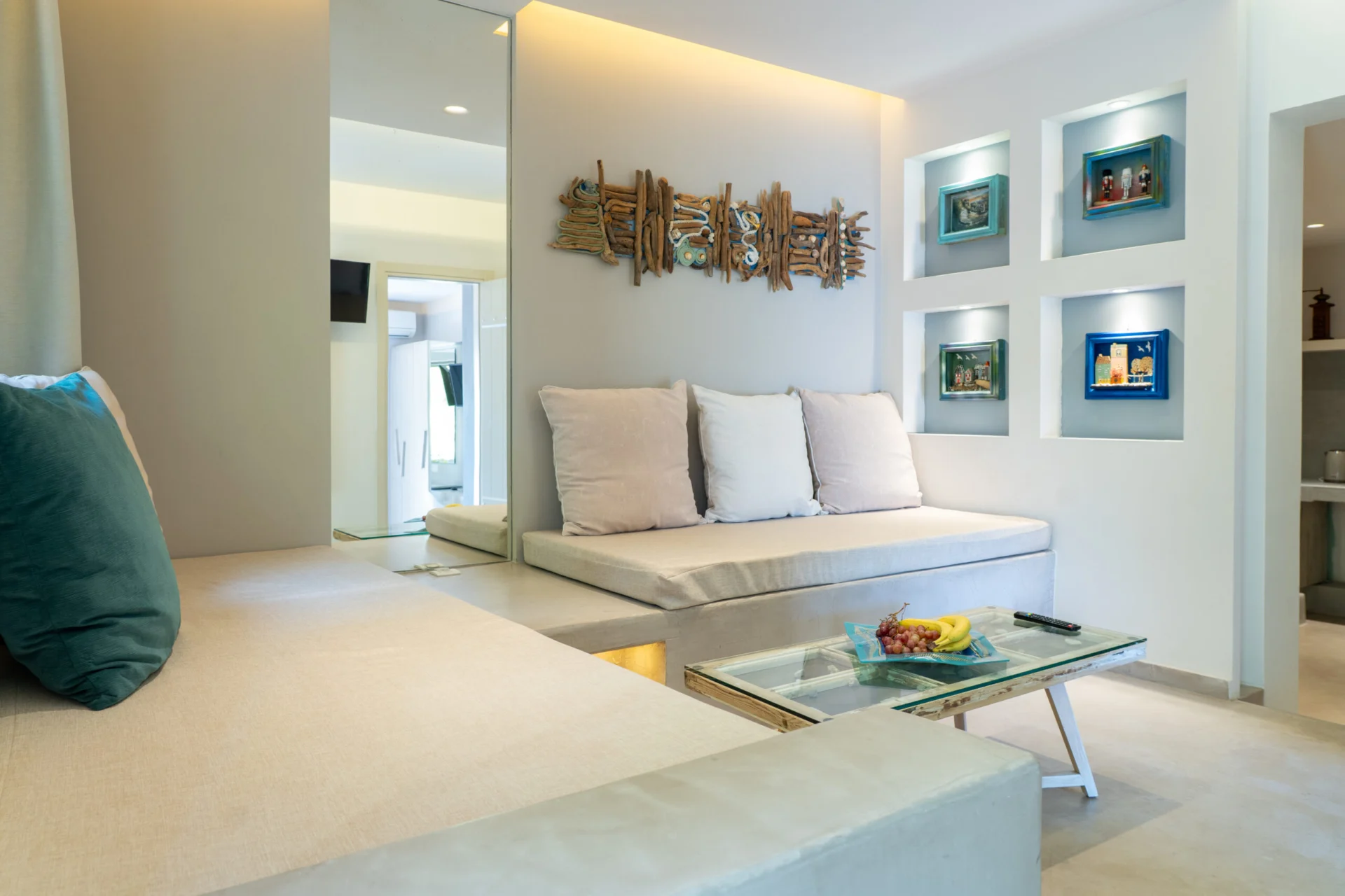 A built-in sofa with driftwood art and lit wall alcoves in the Alessia Family Suite at CORE Luxury Suites, Skiathos.