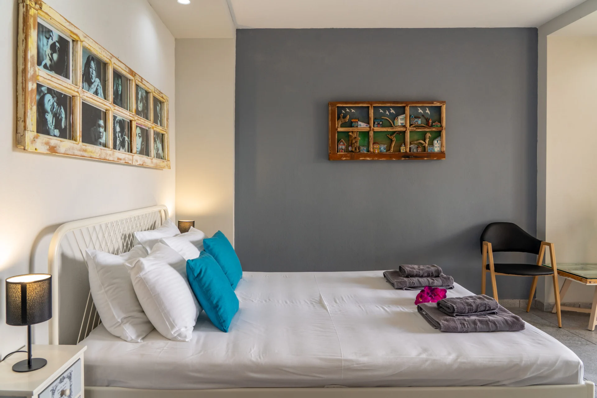Un letto con cuscini color ottanio sotto opere incorniciate su una parete grigio tenue nella Alex 1 Classic Suite di CORE Luxury Suites, Skiathos.