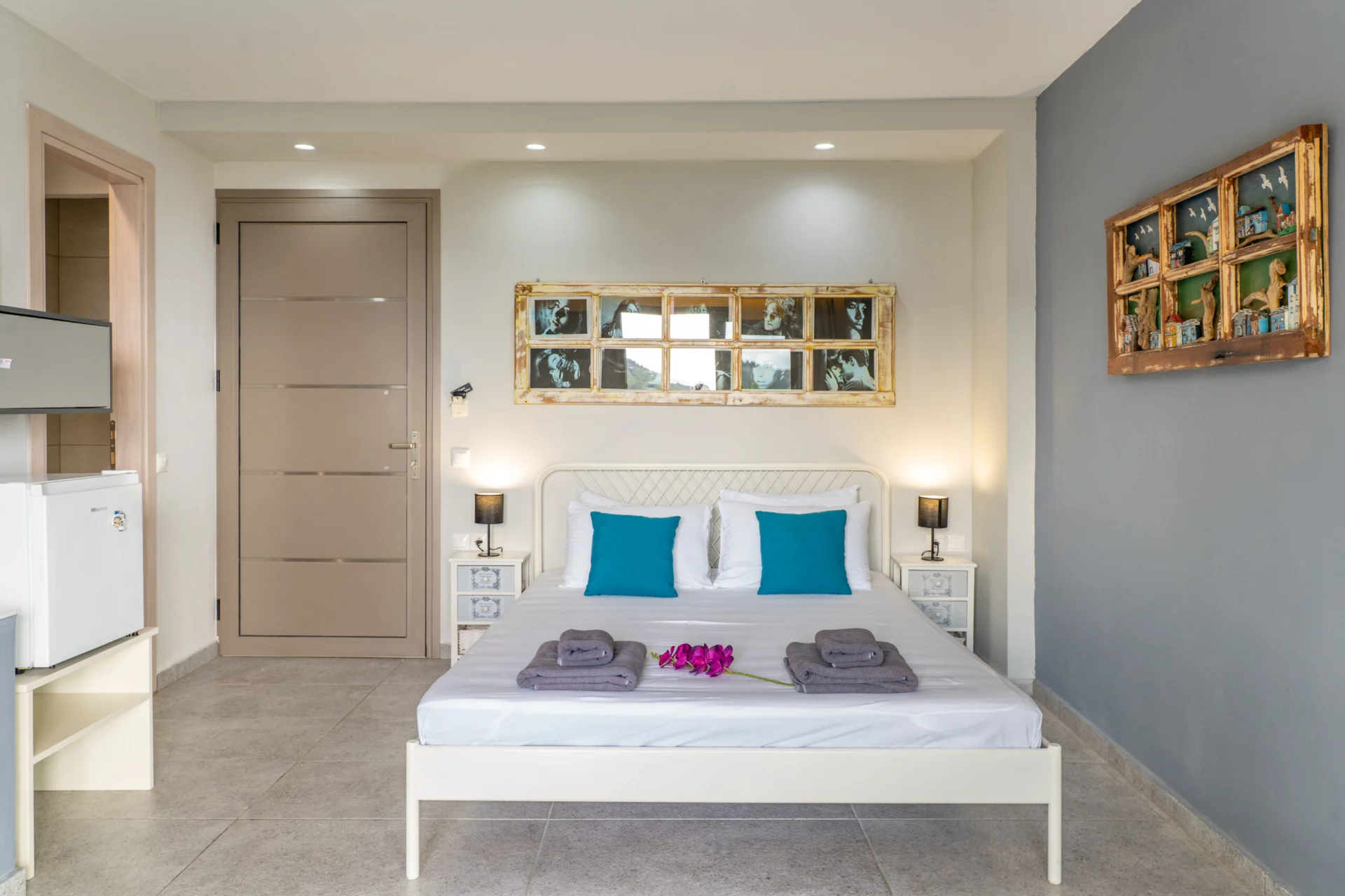 A white bed with teal cushions between two framed mirrors in the Alex 1 Classic Suite at CORE Luxury Suites, Skiathos.