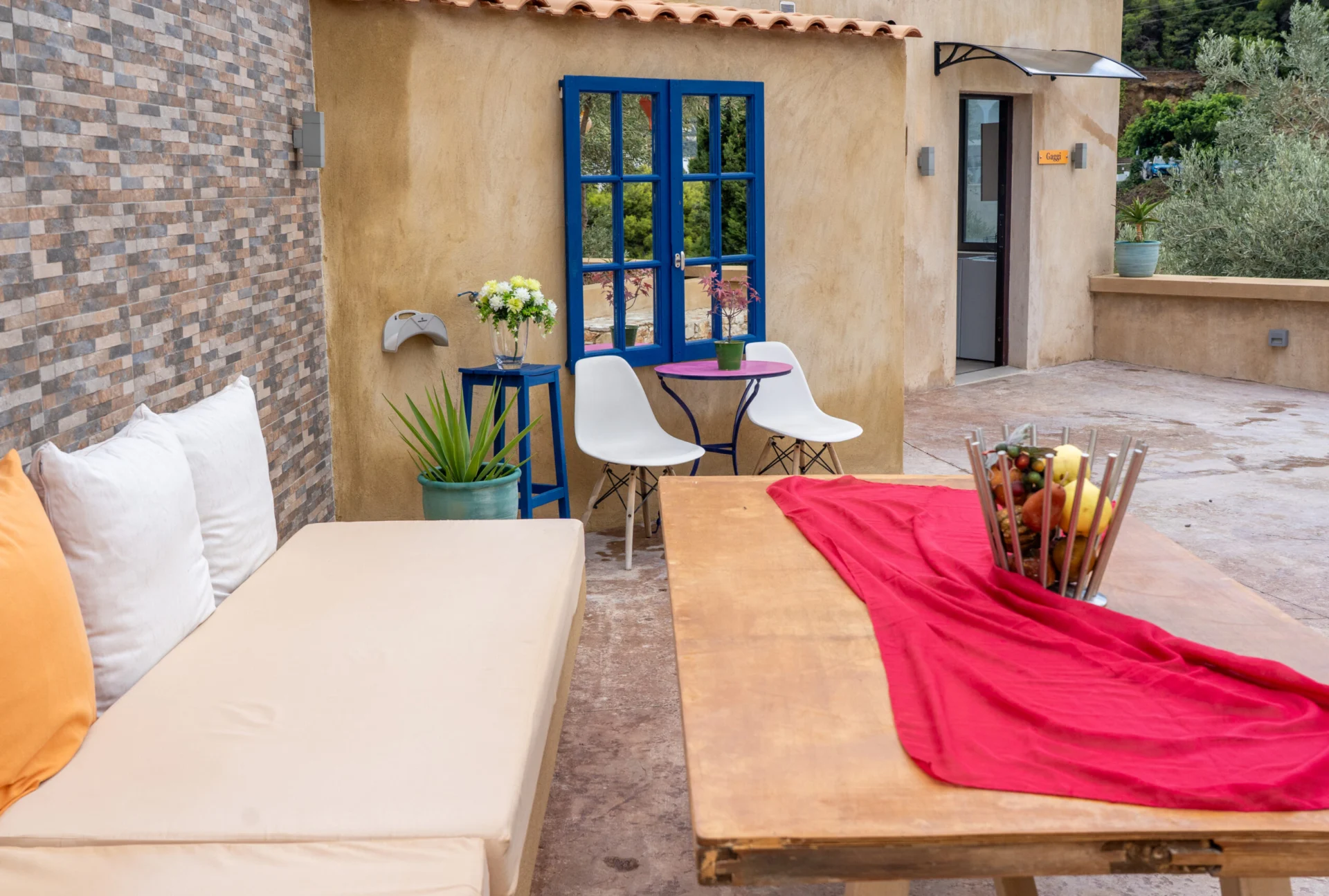 A private courtyard with blue shutters, a sofa and a table in the Alex 3 Superior Suite at CORE Luxury Suites, Skiathos.