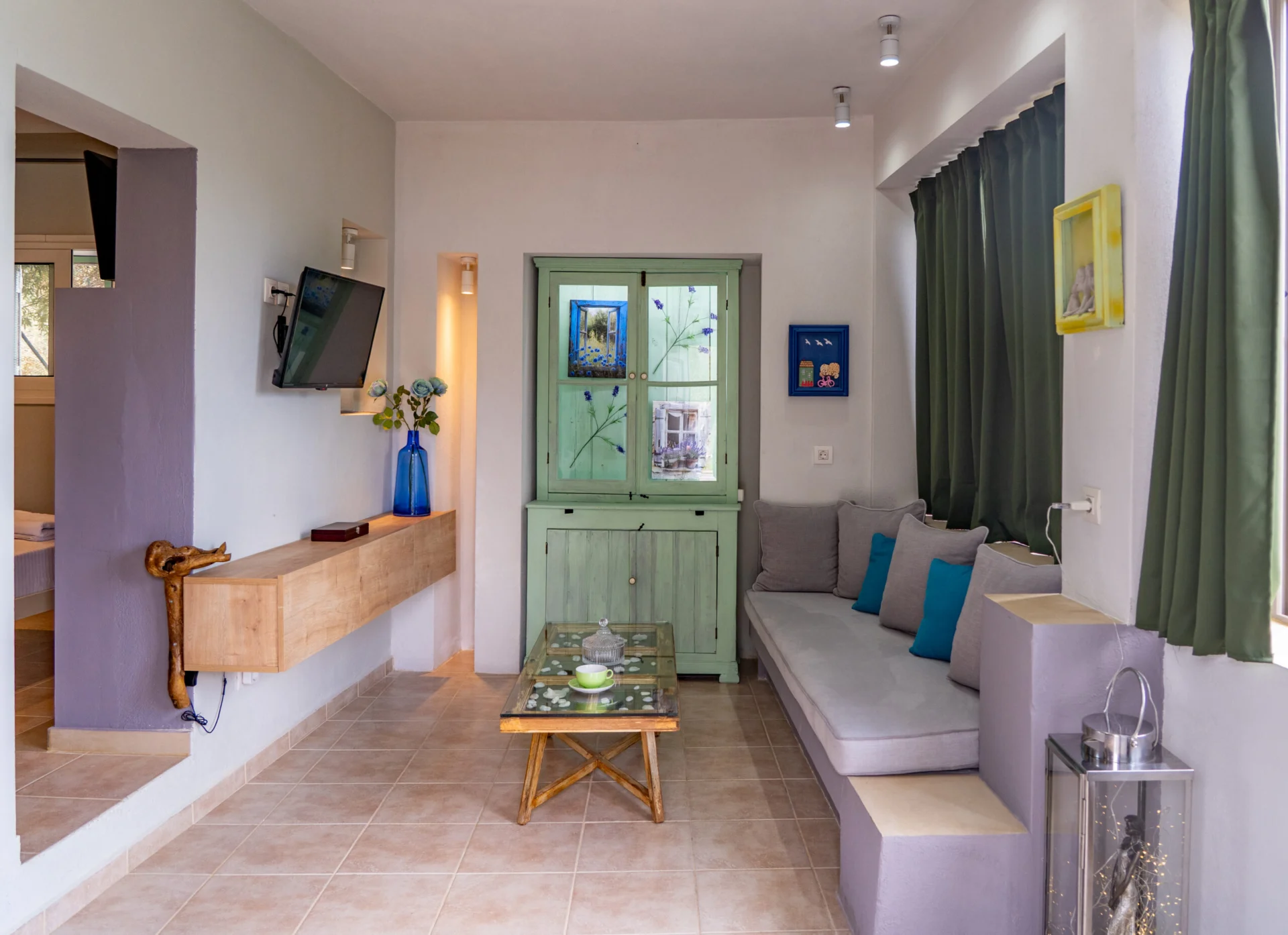 Un soggiorno con mobile verde, cuscini color ottanio e divano a panca nella Alex 3 Superior Suite di CORE Luxury Suites, Skiathos.