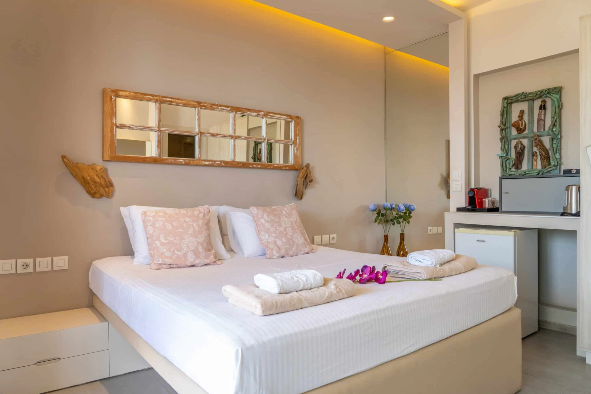 A bedroom with a driftwood mirror and the kitchenette alongside in the Demi Classic Suite at CORE Luxury Suites, Skiathos.
