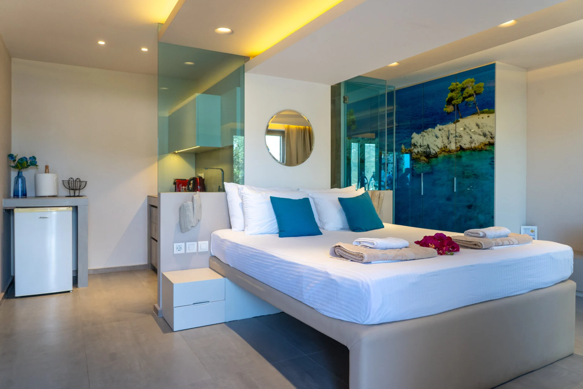 A bedroom with teal cushions, a kitchenette and the sea beyond in the Georgia Superior Suite at CORE Luxury Suites, Skiathos.