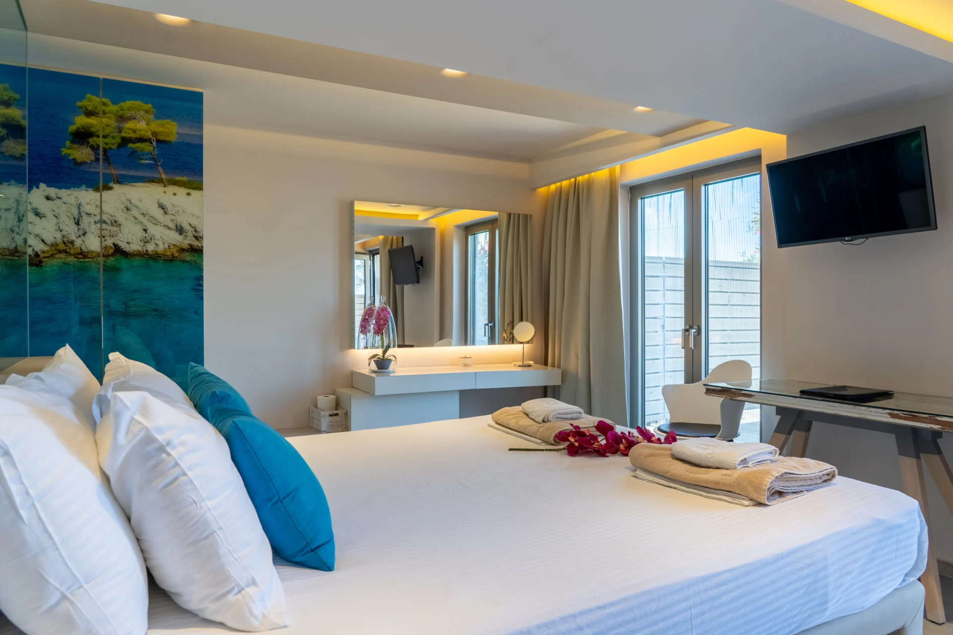Un letto con cuscini color ottanio sotto un dipinto del mare nella Georgia Superior Suite di CORE Luxury Suites, Skiathos.