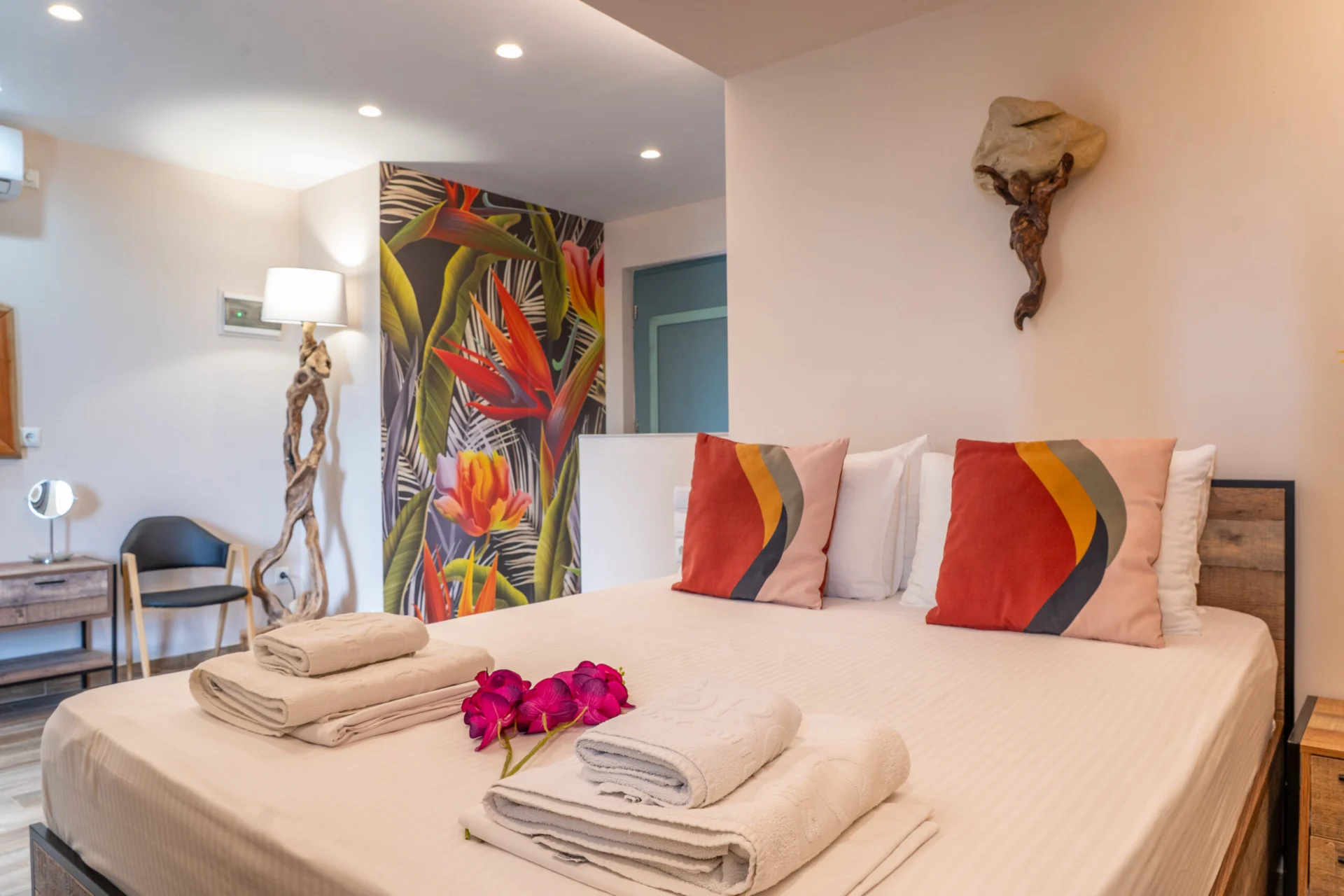 A bedroom with a tropical mural, coral cushions and a desk in the Madalena Superior Suite at CORE Luxury Suites, Skiathos.