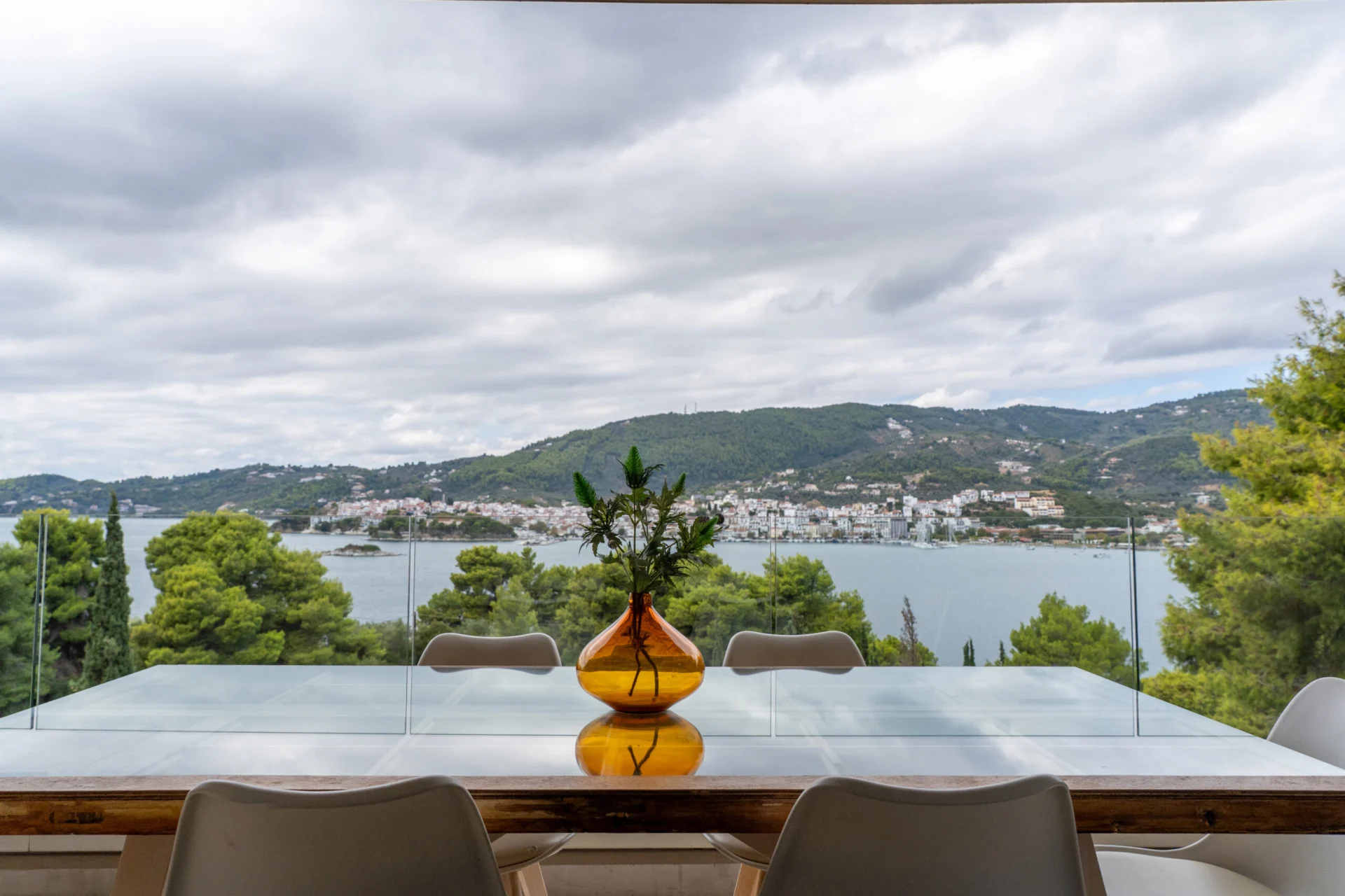 Un tavolo da pranzo sulla terrace sopra la baia, sotto un cielo grigio tenue, nella Stavros Family Suite di CORE Luxury Suites, Skiathos.