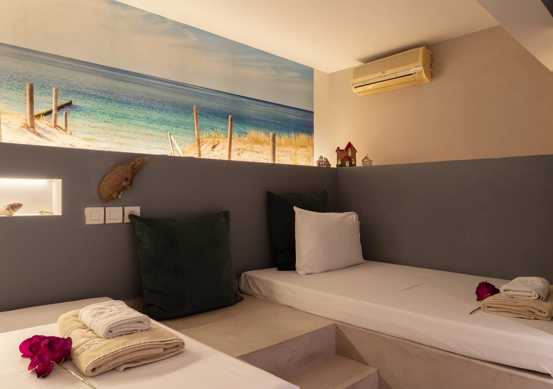 Due letti singoli sotto il murale dipinto raffigurante la spiaggia nella Vassiliki Deluxe Suite di CORE Luxury Suites, Skiathos.