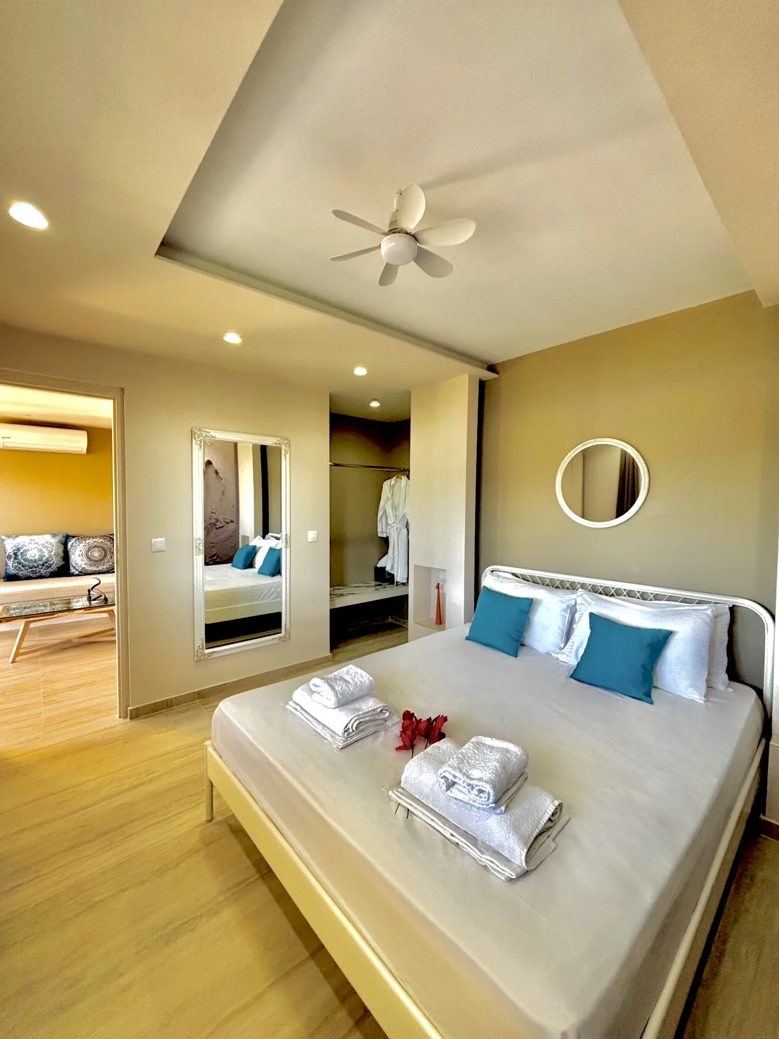 Ein Bett mit petrolfarbenen Kissen unter einem Deckenventilator und Spiegel in der Cassy Deluxe Suite bei CORE Luxury Suites, Skiathos.