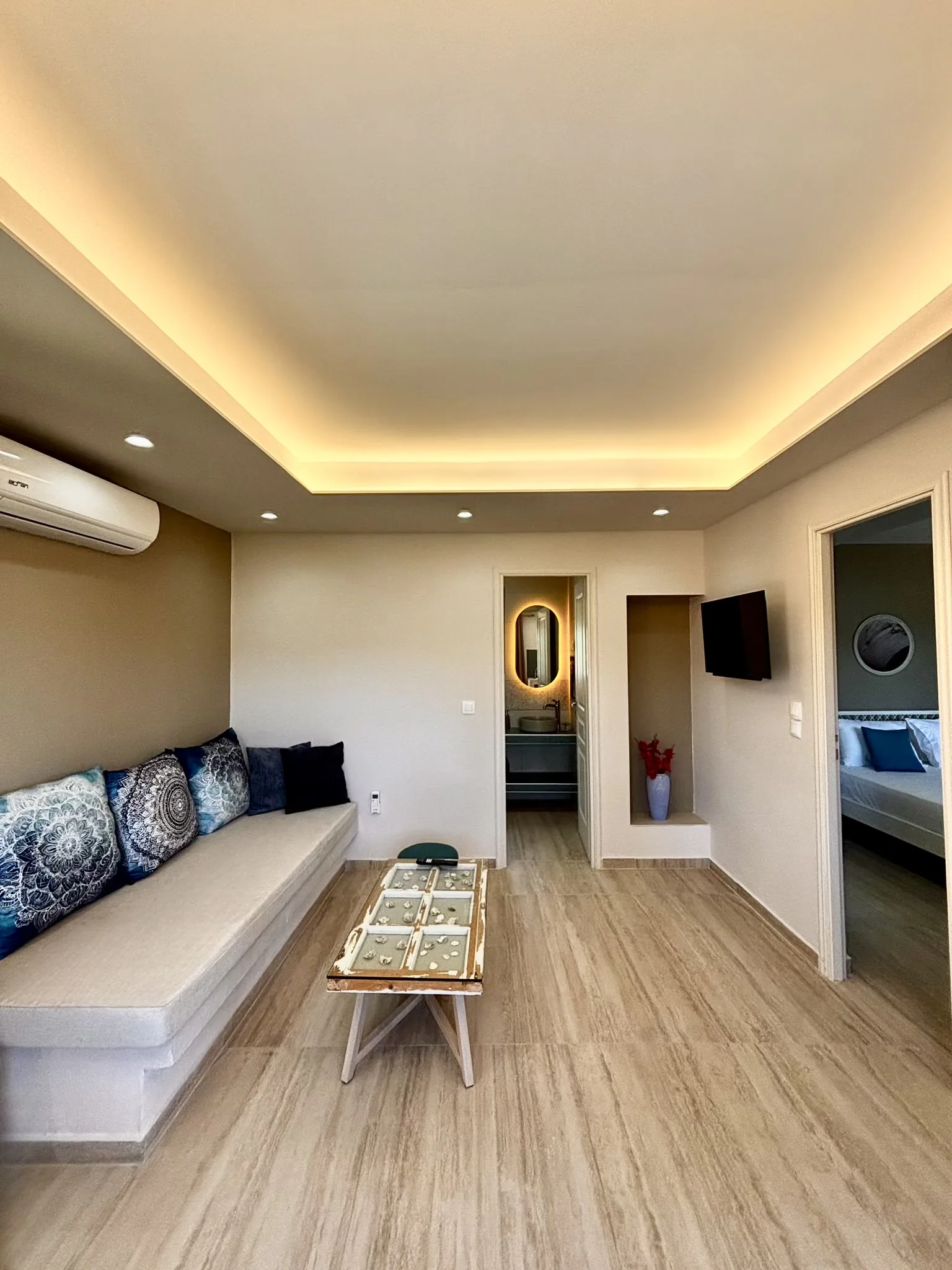 Ein langes eingebautes Sofa mit blau gemusterten Kissen in der Cassy Deluxe Suite bei CORE Luxury Suites, Skiathos.