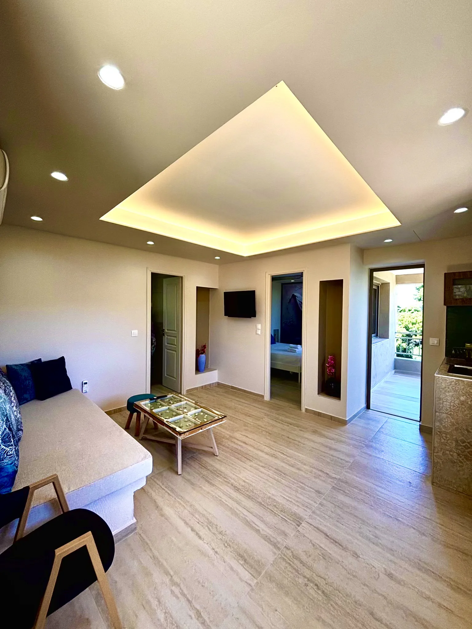 Ein Wohnzimmer mit geöffneter Tür zur terrace und den Pinien in der Cassy Deluxe Suite bei CORE Luxury Suites, Skiathos.