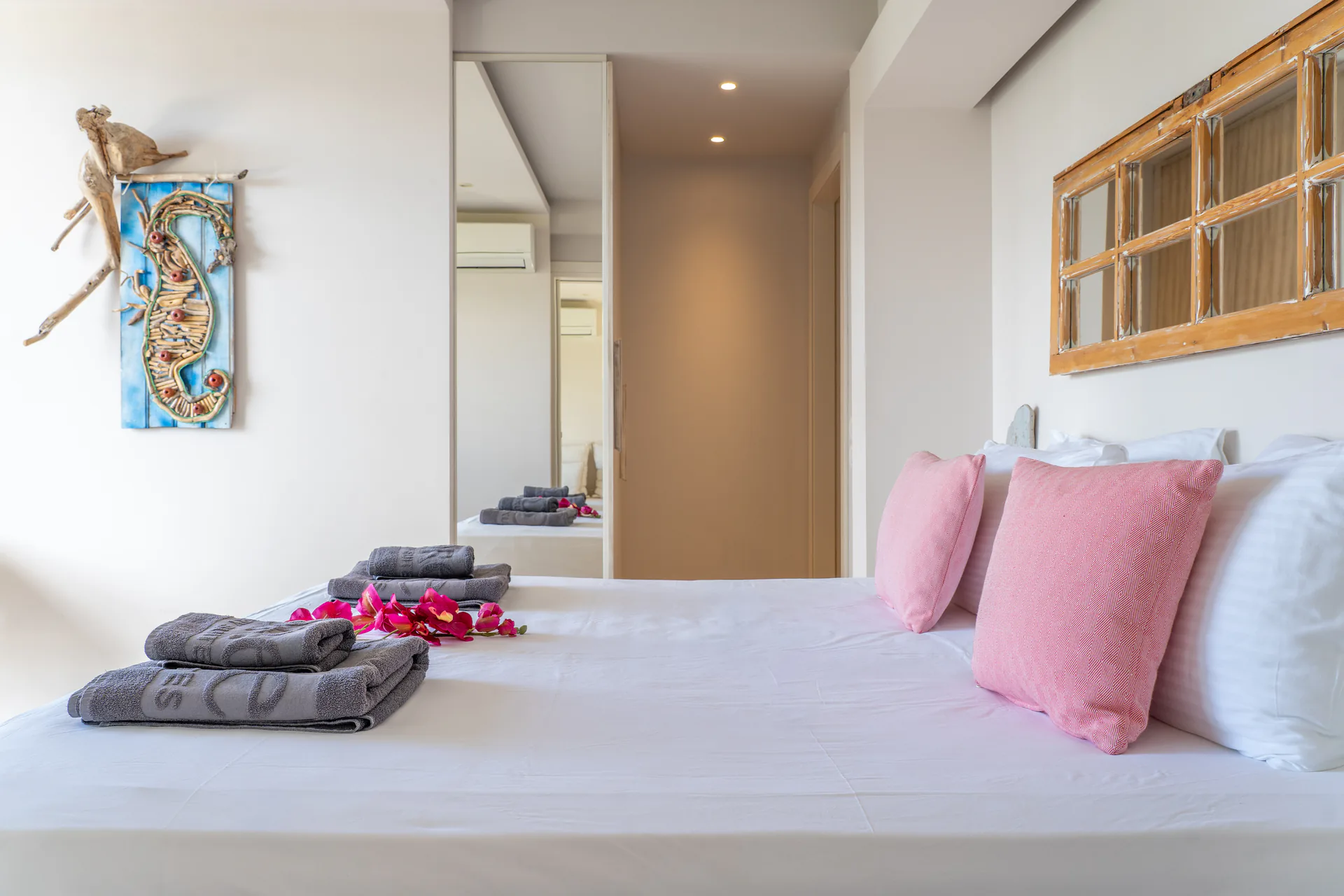 A bed with pink cushions beside a painted seahorse panel in the Daniel Signature Suite at CORE Luxury Suites, Skiathos.