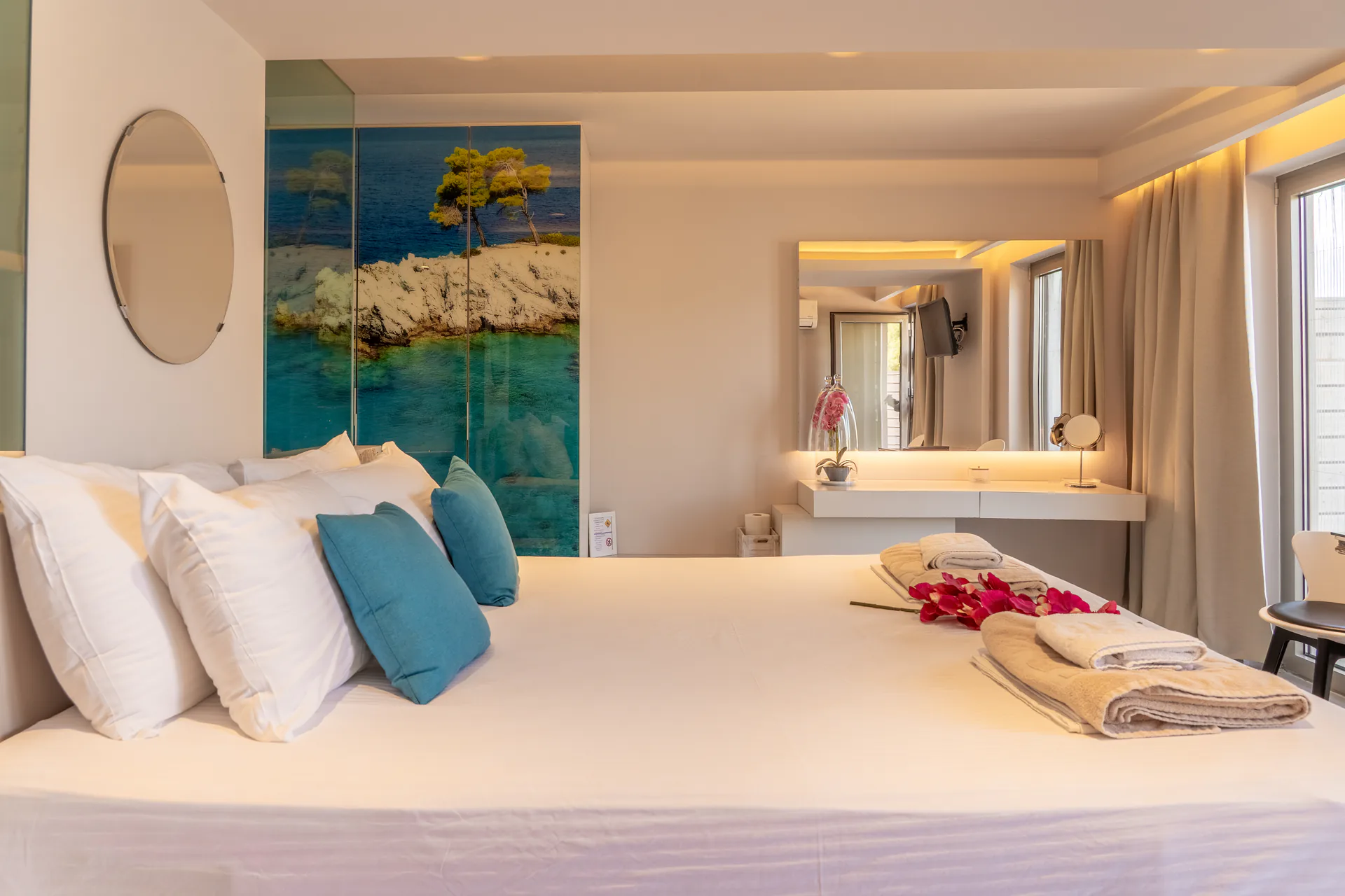 Un letto con cuscini color ottanio sotto un trittico dipinto con paesaggio marino nella Georgia Superior Suite di CORE Luxury Suites, Skiathos.