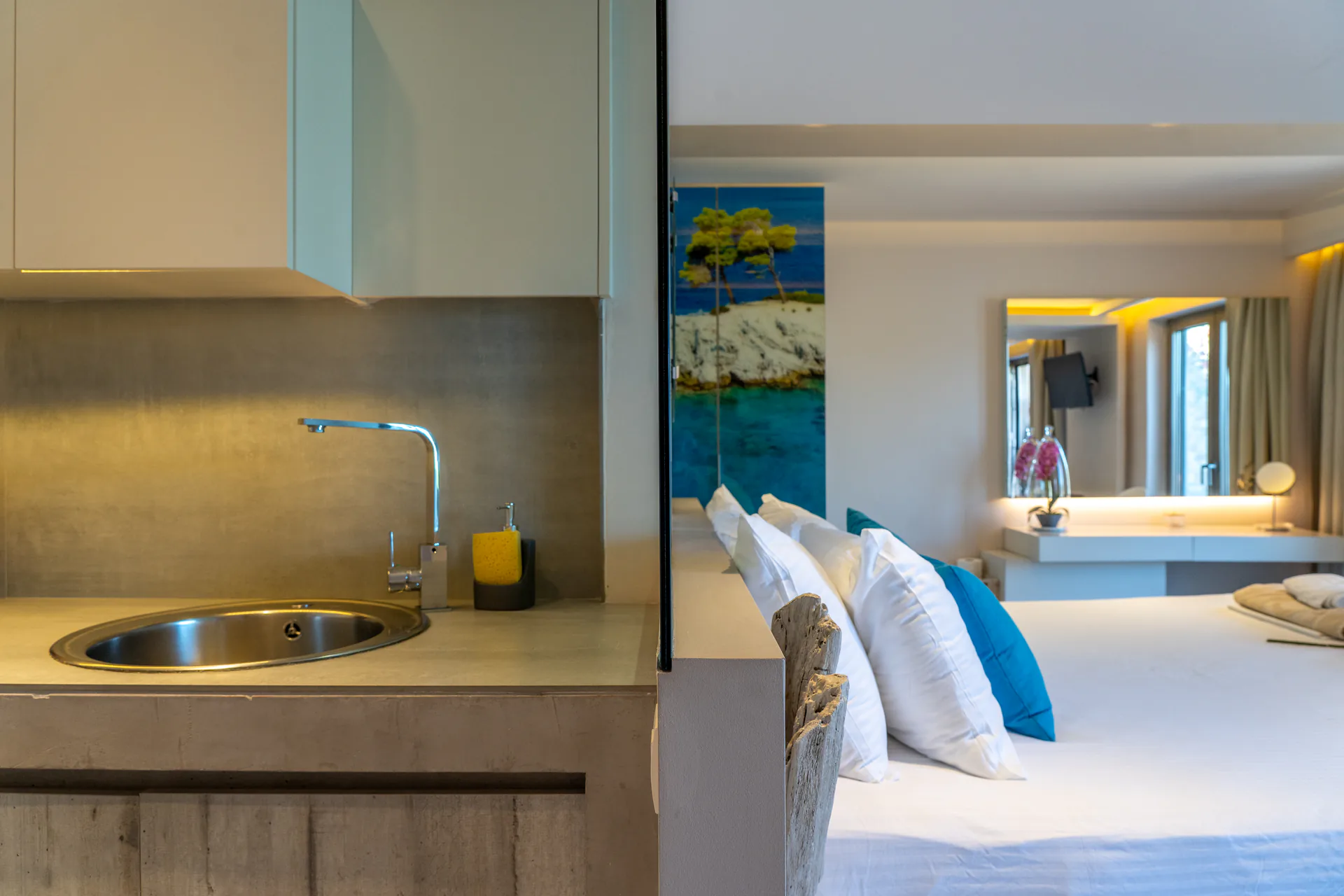 Il piano di lavoro dell’angolo cottura, con il letto e i pannelli marini sullo sfondo, nella Georgia Superior Suite di CORE Luxury Suites, Skiathos.