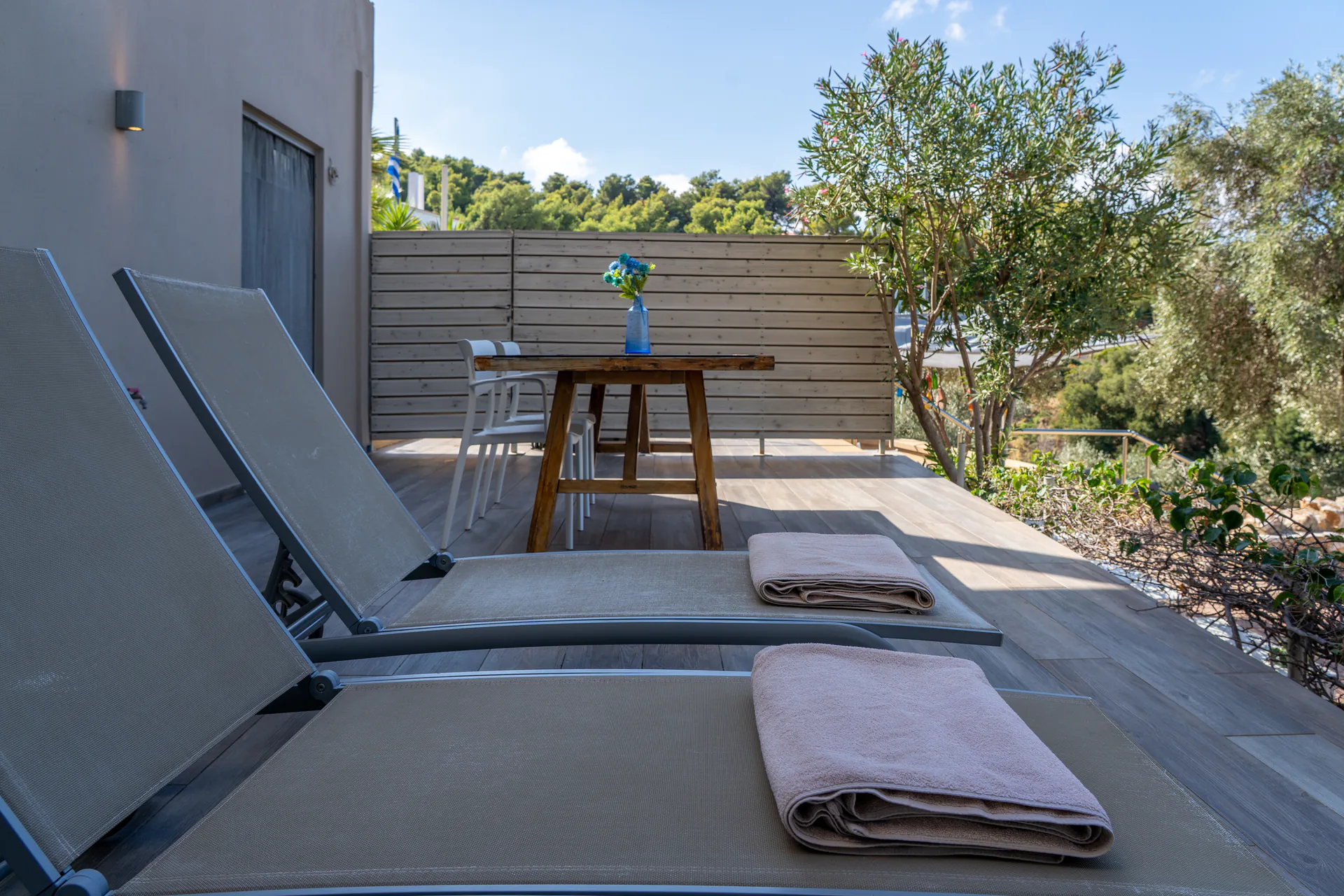 Due lettini e un tavolo in legno accanto a un ulivo nella Georgia Superior Suite di CORE Luxury Suites, Skiathos.