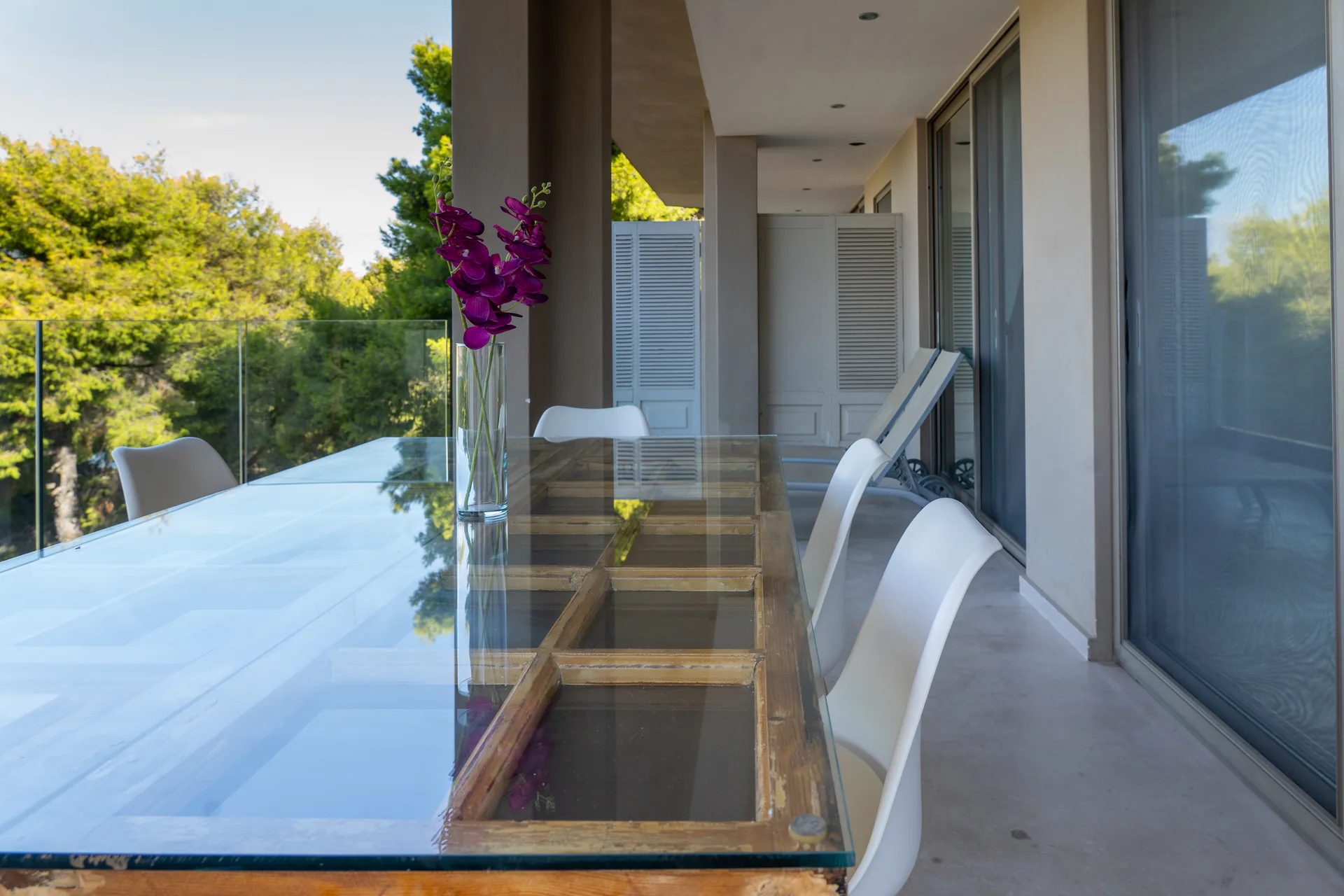 A long glass-topped dining table with an orchid in the Kassandra Signature Suite at CORE Luxury Suites, Skiathos.