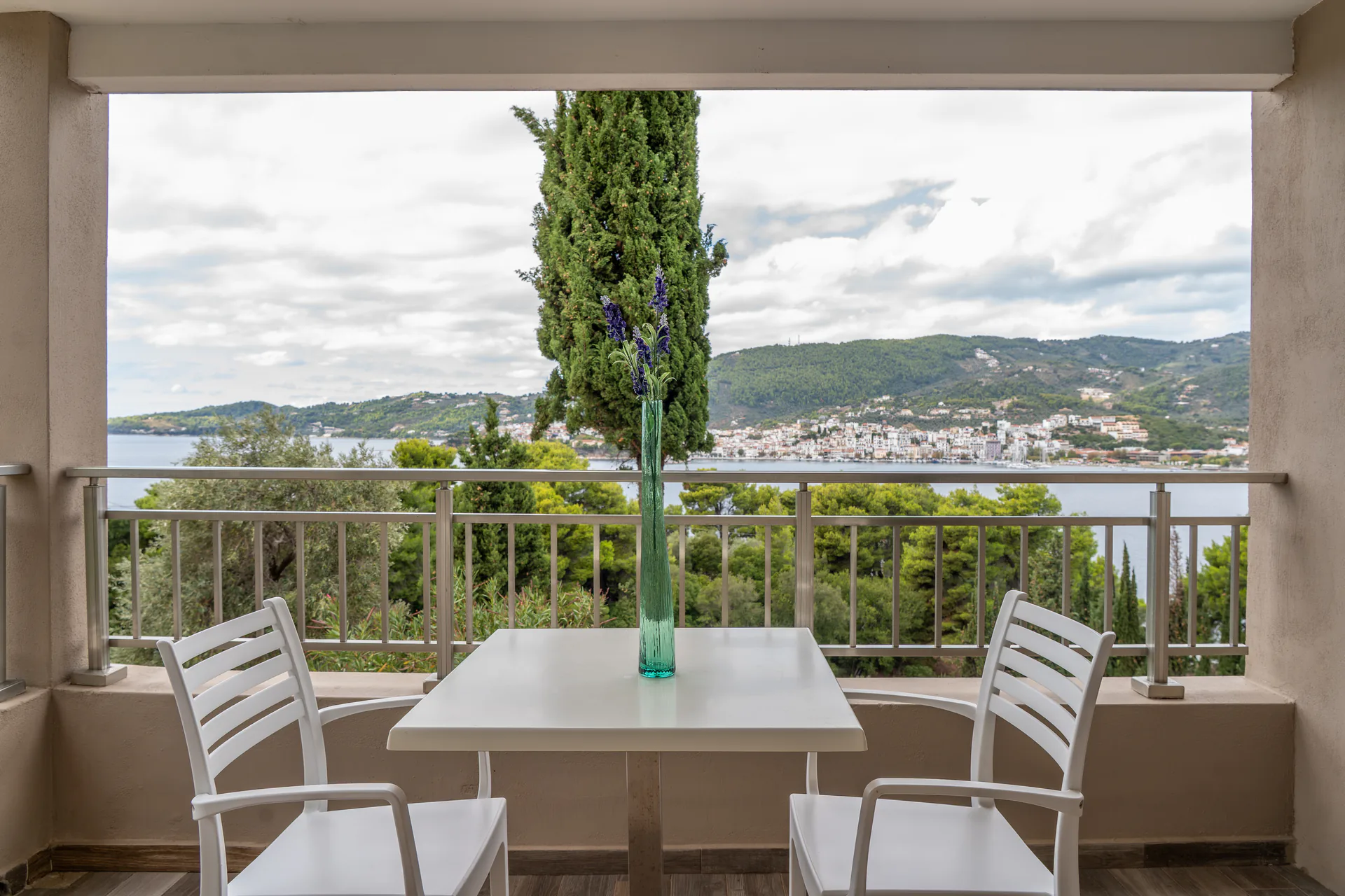 A balcony table looking past a cypress to the bay in the Madalena Superior Suite at CORE Luxury Suites, Skiathos.