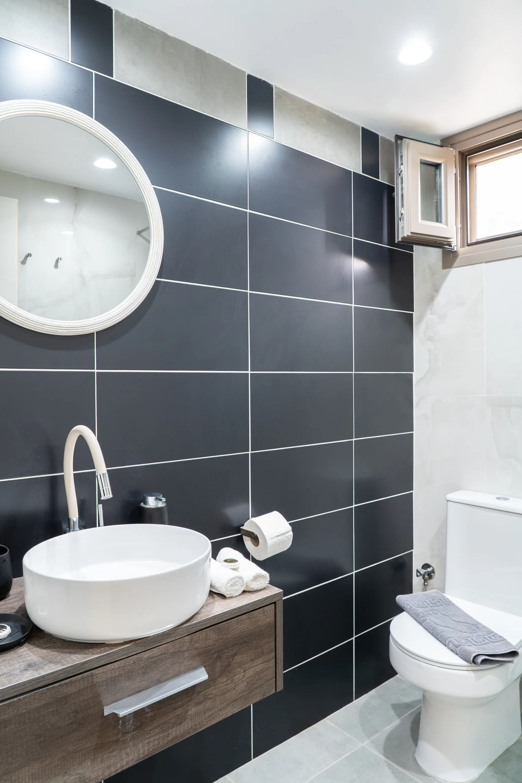 A round basin on a timber vanity against charcoal tiles in the Madalena Superior Suite at CORE Luxury Suites, Skiathos.