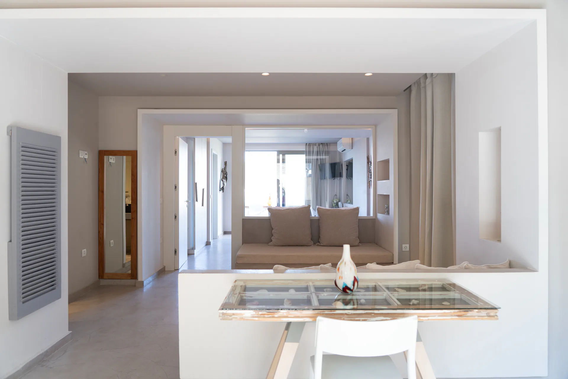 A glass-topped dining table with the sofa beyond in the Patrick Family Suite at CORE Luxury Suites, Skiathos.