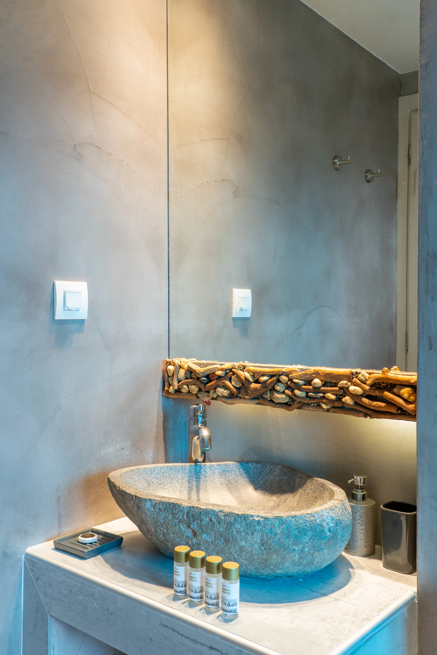 Un lavabo in pietra sotto una mensola in legno portato dal mare e ciottoli nella Stavros Family Suite di CORE Luxury Suites, Skiathos.