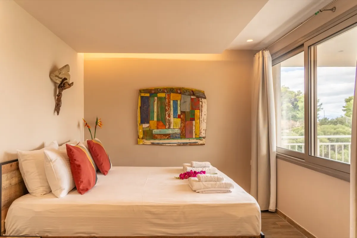A bed with coloured cushions beneath a painted panel