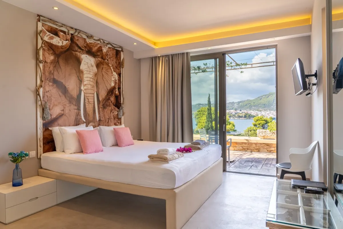 A bed beneath a driftwood piece, with the sea through the open door
