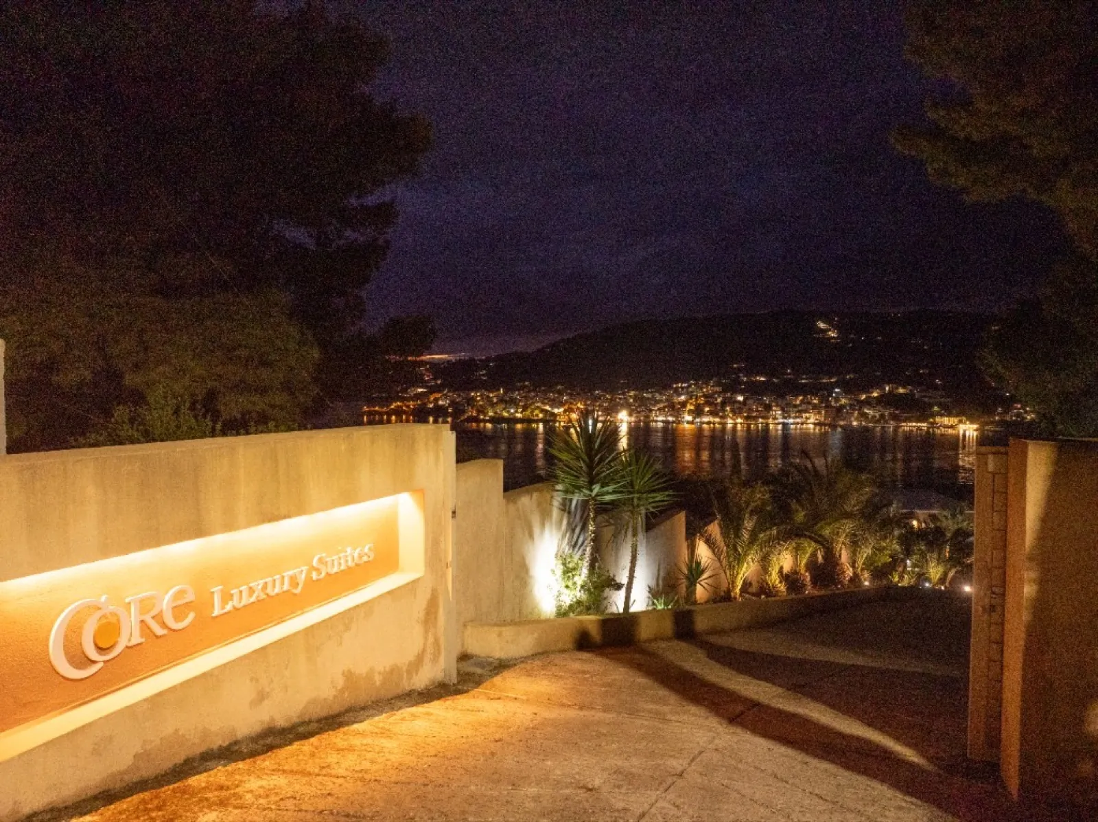 CORE Luxury Suites entrance sign lit at night overlooking the bay