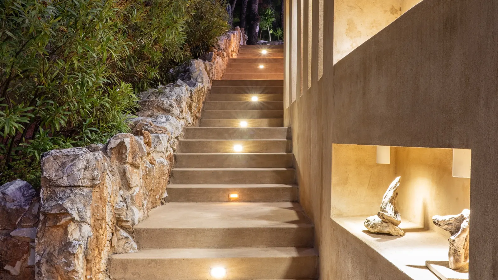 Lit stone steps climbing between the suites after dark