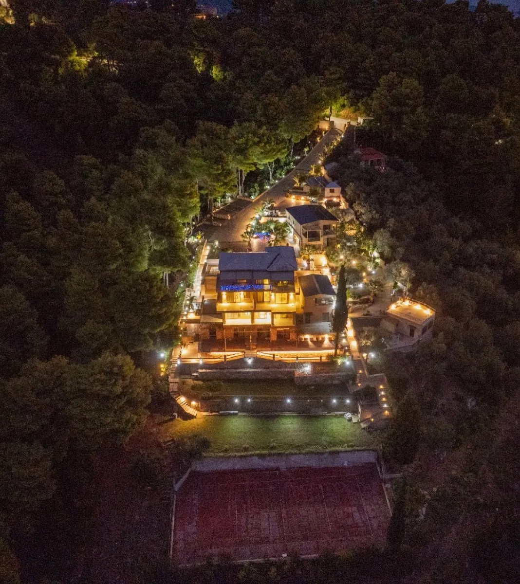 Aerial night view of CORE with the tennis court below the lit suites