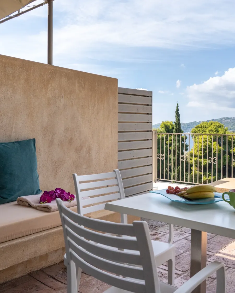 A terrace corner with cushions, fruit on the table and the bay beyond