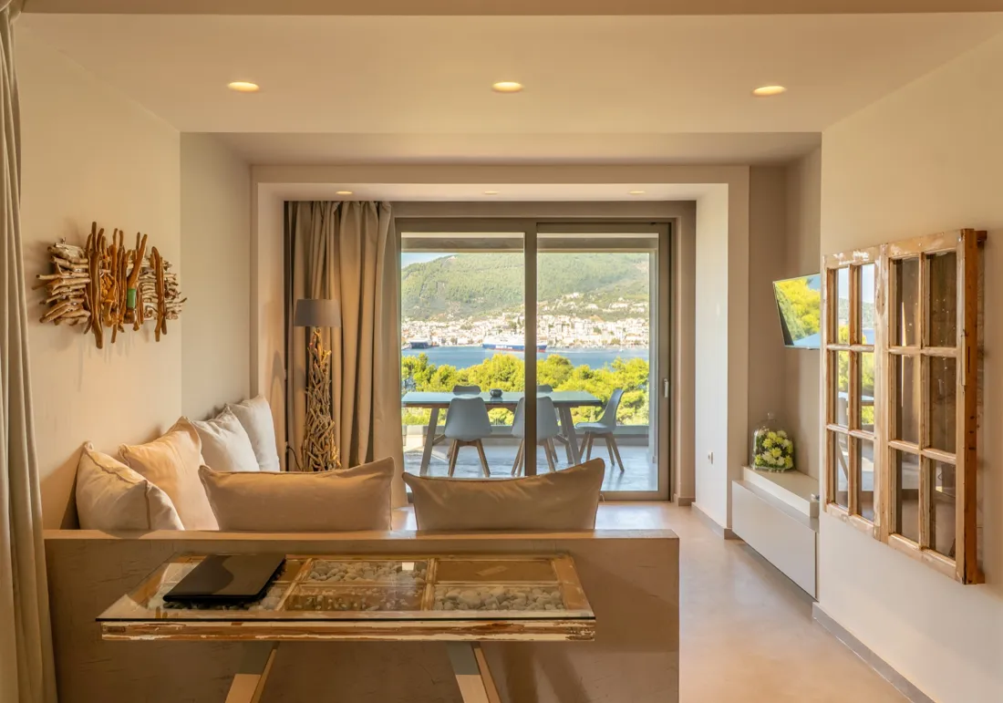 A suite living room with driftwood art and the terrace door open to the bay, CORE Luxury Suites Skiathos